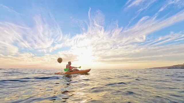 Kayaking Sunset Ocean man paddles his orange kayak across the sea under a golden sky during an adventurous summer evening