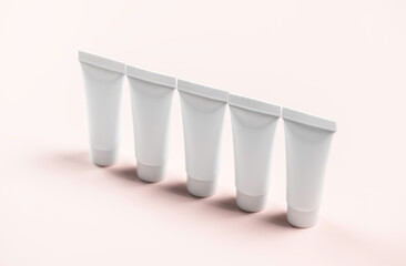 Five white tubes stand in row on pink background.