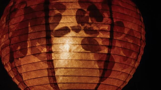 Glowing paper lantern with leaf design at night