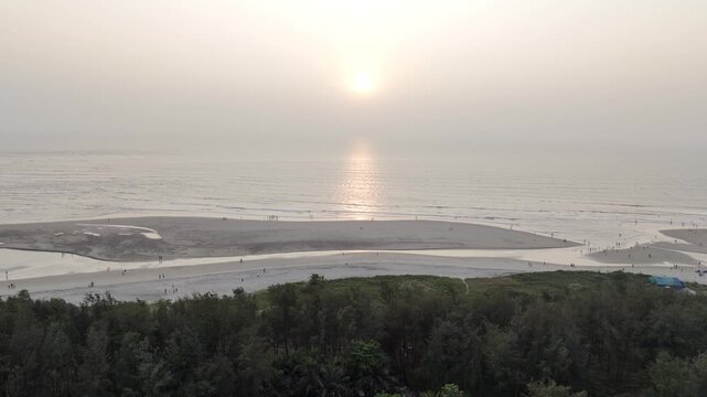 Sunset view of Morjim turtle nesting beach, Goa in winter, showcasing lush coastal greenery with coconut palms and native vegetation, overlooking the Arabian Sea under warm golden light 