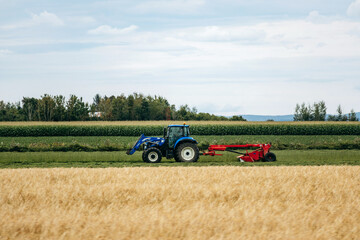 Fototapeta premium Saint-Gedeon, Canada - August 19, 2025: Tractor working in agricultural field during summer harvest season