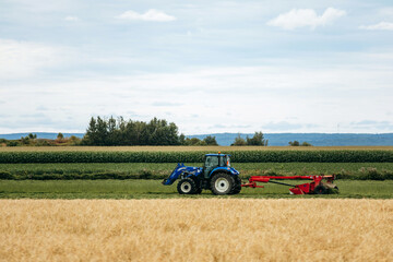 Fototapeta premium Saint-Gedeon, Canada - August 19, 2025: Tractor working in agricultural field during summer harvest season