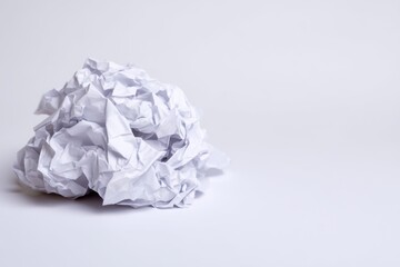 Close-up shows discarded crumpled white paper ball on a white background implying mistake or frustration
