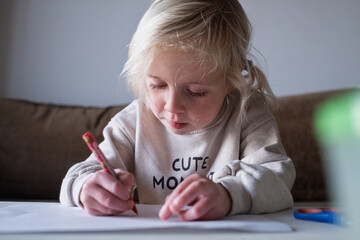 Preschool child doing homework and practicing writing skills, early education concept.