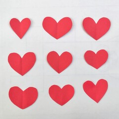 Pattern of Nine Red Paper Hearts Arranged in a Grid on White Background