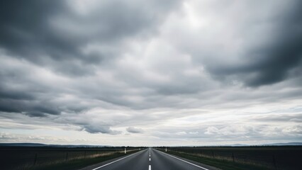 Empty asphalt road leading to the horizon under a dramatic cloudy sky.