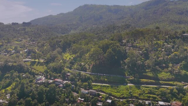 Aerial View of a Passenger Train Passing Through Lush Green Hills