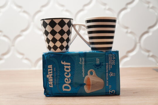 Two decorative coffee cups balanced on a pack of Lavazza Decaf coffee