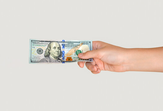 Hand holding a 100 dollar bill. Man hand is holding dollar bill. Money, cash. Hand taking a banknote of 100 dollar. Woman's hand holding one hundred dollar banknote