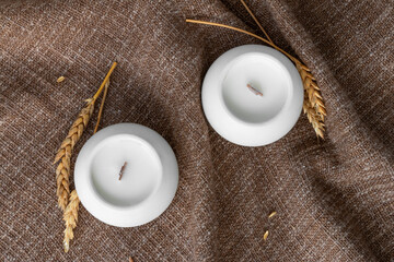 aromatic candles with wooden wick in plaster candlestick, close-up on burlap background, handmade concept
