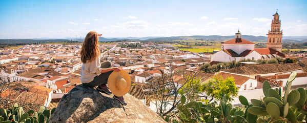 Woman sitting on rock enjoying beautiful panoramic view of city landscape in Portugal