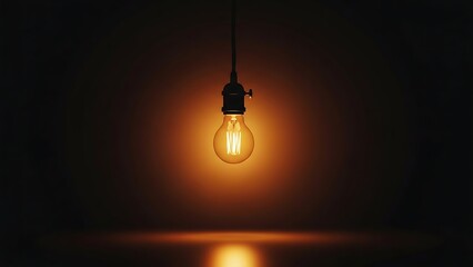 Warm golden light bulb hanging in total darkness providing a central focal point of inspiration and bright creative energy.