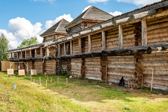 The impressive wooden walls of a reconstructed Old Slavic fortress, made of round, hewn logs. Old barracks and boyar chambers. A bright, sunny day.