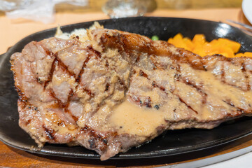 熱々の鉄板で提供されるジューシーな厚切り牛ステーキ