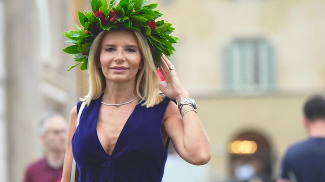 Happy female graduate with diploma and laurel wreath in front of Pisa Cathedral complex at sunset
