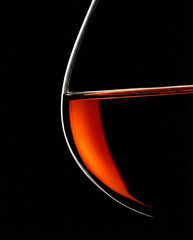 An elegant, minimalist close-up capturing the warm orange glow and sharp rim of a glass containing aged amber spirit.