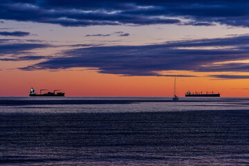 Sagome di navi da trasporto e barca a vela al tramonto viste dal lungomare di Salerno (Campania , Italia)	
