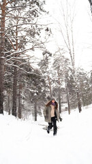 A young woman relaxes during a walk in a winter forest with her dog.