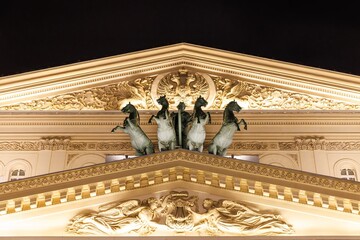 Majestic horses adorn the stunning rooftop of an iconic theater illuminated at night