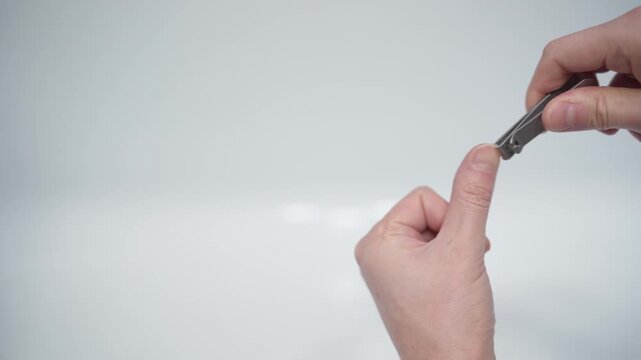 Cutting nails on a man's hand with nail tongs on a white background. Care for hands.