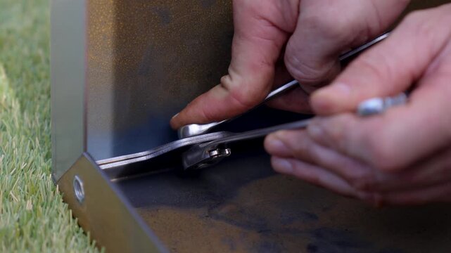 close-up of Caucasian hands doing DIY, one holding the key and the other holding the tool to turn the screw and tighten it
