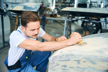 Auto mechanic worker polishing car at automobile service station shop by power buffer machine