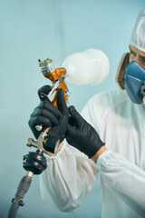 Close up of mechanic working in car spray room, holding spray compressor