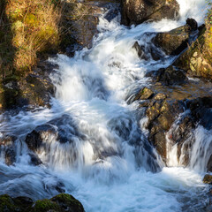 closeup of a fast flowing waterfall splashing over rocks