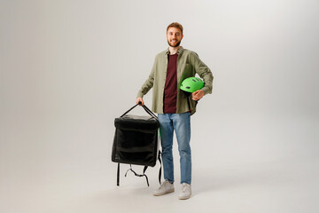 Delivery worker holds food bag and helmet in studio for job promotion in simple setting