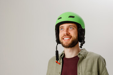 Man wearing a green helmet smiles and looks upward inside a light-colored room during a fun moment