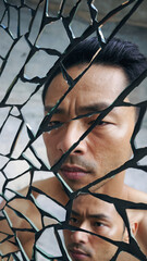 Man peering through shattered mirror fragments, reflecting a contemplative expression.