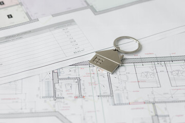 Keys and house plans on the desk show a home purchase process at an office with paperwork and detailed layouts