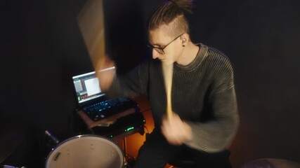 Focused musician crafting rhythms in dimly lit studio environment