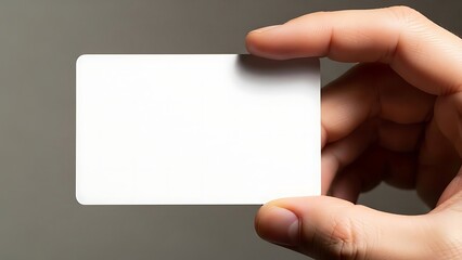 Obraz premium Hand holding blank white plastic card close up against dark muted background