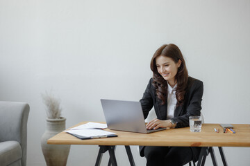 Professional woman working on laptop at desk in bright office space during daytime