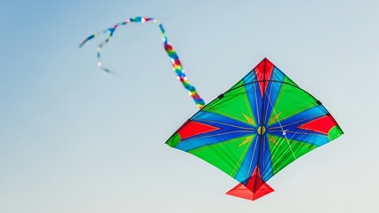 Colorful kite with rainbow tail flying against clear blue sky