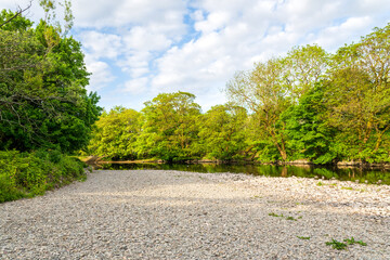 Obraz premium Berge de galets et rivière bordée d’arbres à Kendal, paysage naturel du Lake District au printemps, Cumbria, Angleterre