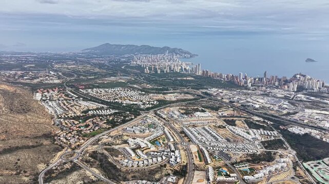 bright coastal development with dense housing and highrise skyline, winding roads leading to marina and bay