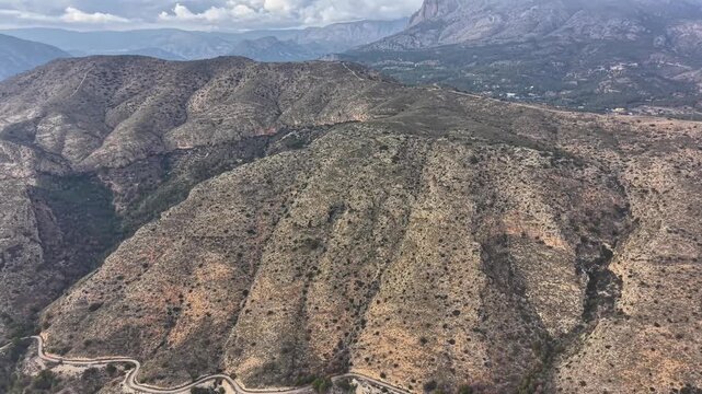 eroded hills with winding road and patterned ridges in dry terrain. aerial view shows droughttinted slopes,