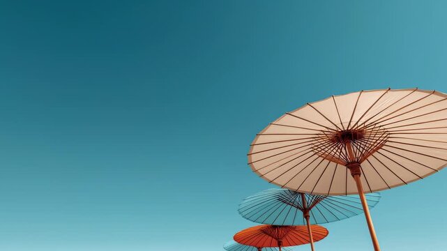 Serene blue sky with white, blue, and orange umbrellas hanging in an abstract art display with ample copy space