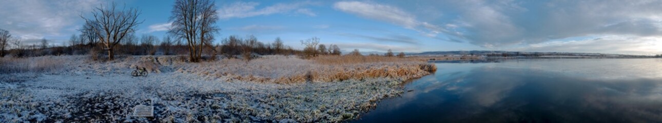 Panorama of winter lake with fog and forest