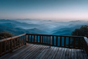 Fototapeta premium View from a wooden deck with railing, overlooking a vast mountain range covered in morning mist, layers of blue mountains fading into distance.