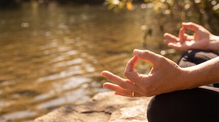 Woman sits in lotus pose near lake with hands in mudra as sun shines on water surface and nature surrounds the scene