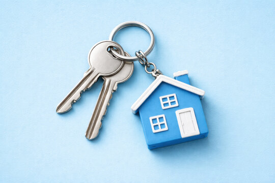 House keys with a small blue house keyring on a bright blue background. Concept of real estate, home ownership, new beginning. Mortgage, purchase of real estate, investment, new apartment, rent, sale.