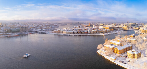 Fototapeta premium Amazing view of Snow covered Stockholm old town, Sweden after a winter storm, with a boat going towards the island.