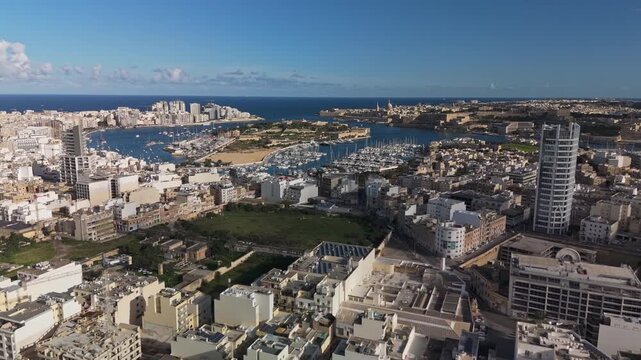 Aerial view of Malta's vibrant harbor cityscape around the Manoel Island, including Sliema, Msida, Ta' Xbiex and Valletta, highlighting the Mediterranean island's urban charm and coastal allure.