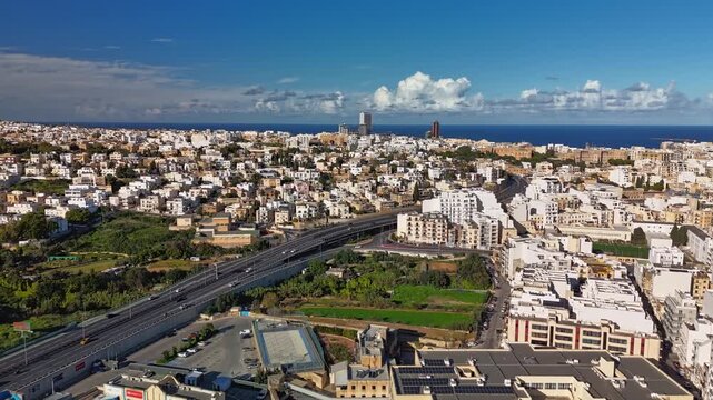 Aerial timelapse from Msida, Malta, on a sunny winter day with moving cars and clouds over the bustling cityscape of Kappara, San Ġwann, St Julian's and Swieqi areas.
