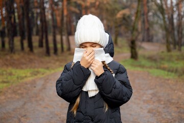 9-year-old girl blowing her nose into a paper napkin. Winter flu flare-up. Sick girl