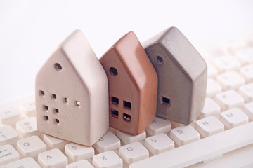 Group of three different houses on white computer keyboard