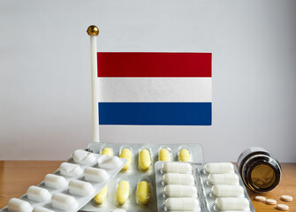Flag of Netherlands with Pills and Capsules. Pharmaceutical Concept
